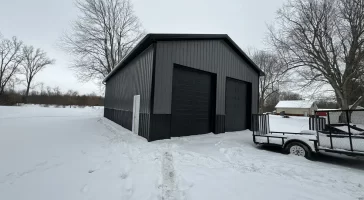 A Stately Pole Barn in East Amherst, NY, showcasing its sharp black and grey color scheme against a snowy backdrop.