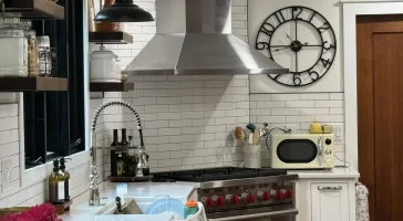 Modern kitchen with stainless steel hood, subway tile backsplash, and farmhouse sink in Amherst, NY after remodel by Stately Kitchen and Bath.