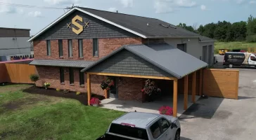 Full view of Stately Builders' Clarence Center office after exterior remodel, featuring new siding, signage, and improved landscaping.