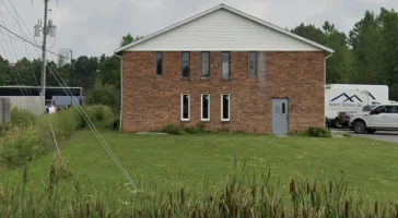 Stately Builders Clarence Center office before exterior remodel, showing the original brick facade with minimal landscaping.