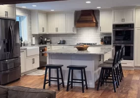 Elegant kitchen with wooden flooring, marble island, and modern stainless steel appliances.