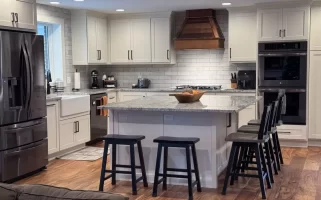 Elegant kitchen with wooden flooring, marble island, and modern stainless steel appliances.