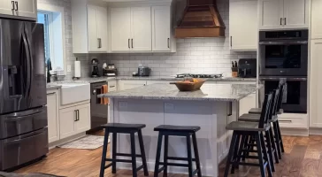 Elegant kitchen with wooden flooring, marble island, and modern stainless steel appliances.