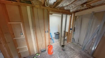 Exposed framing and insulation in a bathroom before remodel by Stately Kitchen and Bath in Gettzville, NY, with construction materials and tools visible.