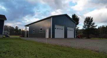 Aerial view of completed post-frame pole barn with dual overhead doors in Clarence Center NY.