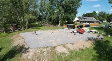 Stately Pole Barn construction site showing foundation piers before post-frame assembly, with tools and equipment in view.