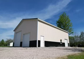 Low angle view of two-tone post-frame garage with overhead doors and walk-in entry, built by Stately in Amherst NY.