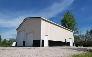 Low angle view of two-tone post-frame garage with overhead doors and walk-in entry, built by Stately in Amherst NY.
