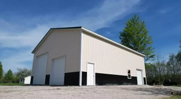 Low angle view of two-tone post-frame garage with overhead doors and walk-in entry, built by Stately in Amherst NY.