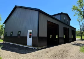 Matte black post-frame barn with reverse gable and overhead door bays, built by Stately in Elma, NY.