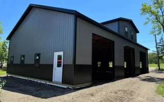 Matte black post-frame barn with reverse gable and overhead door bays, built by Stately in Elma, NY.
