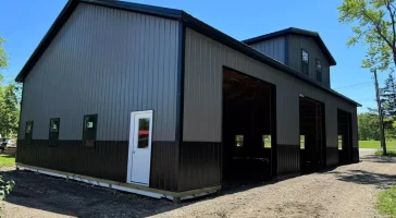 Matte black post-frame barn with reverse gable and overhead door bays, built by Stately in Elma, NY.