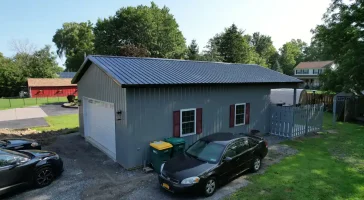 Front view of a 24x36x10 post-frame building in Clarence, NY, constructed by Stately Pole Barns, featuring a modern design with a white garage door.
