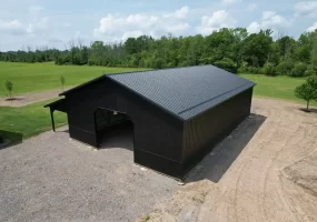 Overhead shot of a matte black pole barn built by Stately Pole Barns in Clarence, NY, featuring strong structural design with Everlast II Steel Panels and a spacious interior.