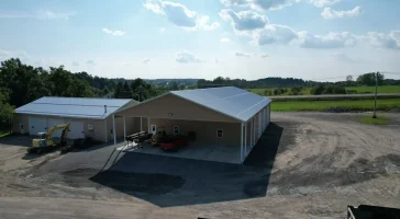 Aerial view of the completed Bennington Highway Department pole barn, highlighting the large structure, parking area, and surrounding equipment storage space, set against a scenic backdrop.